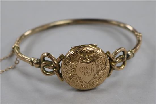 An Edwardian 9ct gold locket bangle with engraved monogram and pierced scroll shoulders.